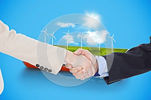 Composite image of smiling business people shaking hands while looking at the camera