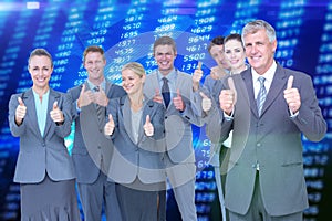Composite image of smiling business team showing thumbs up