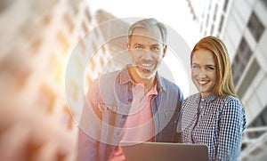 Composite image of smiling businessman and businesswoman are holding a laptop