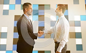 Composite image of smiling businessmen shaking hands
