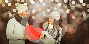 Composite image of smiling couple holding paper heart