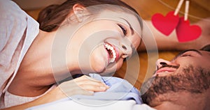 Composite image of smiling couple lying on the floor