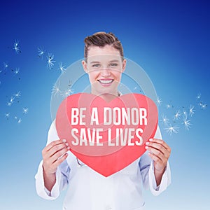 Composite image of smiling doctor holding heart card