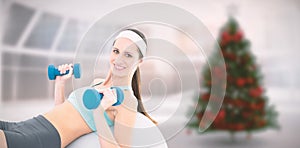 Composite image of smiling fit woman exercising with dumbbells on fitness ball