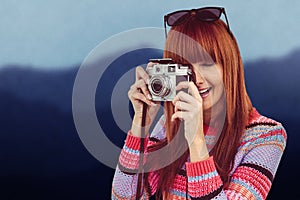 Composite image of smiling hipster woman taking pictures with a retro camera