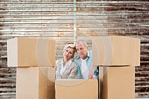 Composite image of stressed older couple with moving boxes