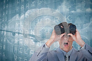 Composite image of suprised businessman looking through binoculars