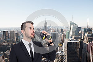 Composite image of surprised businessman standing and holding binoculars