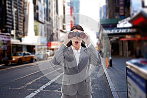 Composite image of surprised businesswoman looking through binoculars