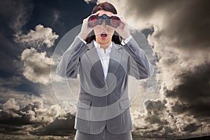 Composite image of surprised businesswoman looking through binoculars