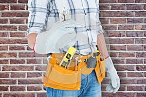 Composite image of technician with tool belt around waist holding pliers