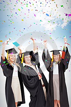 Composite image of three students in graduate robe raising their arms