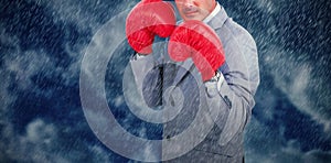 Composite image of tough businessman with boxing gloves