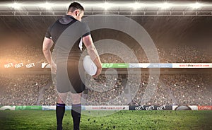 Composite image of tough rugby player holding ball