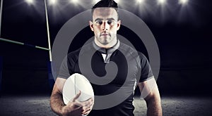 Composite image of tough rugby player holding ball