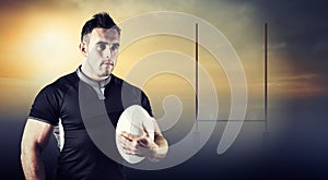 Composite image of tough rugby player holding ball