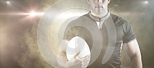 Composite image of tough rugby player holding ball