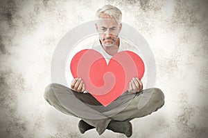 A Composite image of upset man sitting holding heart shape
