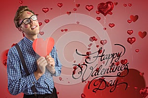 Composite image of valentines text and man holding a red heart