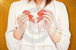 Composite image of woman holding broken heart paper