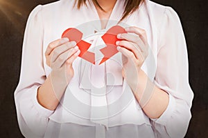 Composite image of woman holding broken heart paper