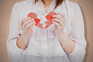 Composite image of woman holding broken heart paper