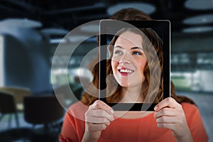 Composite image of woman holding digital tablet in front of her face