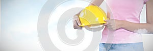 Composite image of woman holding hard hat against grey background