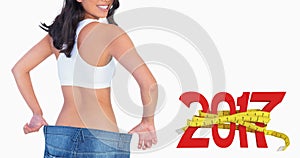 Composite image of woman holding her too big jeans smiling