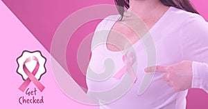 Composite image of woman pointing at breast cancer awareness ribbon on pink background, copy space