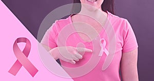 Composite image of woman showing breast cancer awareness ribbon against purple background