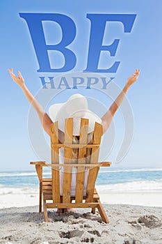 Composite image of woman sitting in deck chair at the beach with arms up