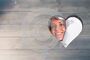 Composite image of young couple looking through paper rip