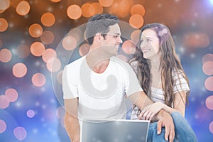 Composite image of young couple sitting on floor using laptop