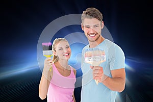 Composite image of young couple smiling and holding paintbrushes