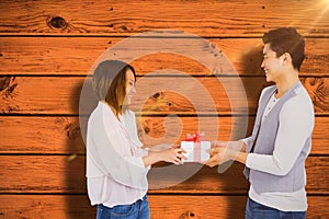 Composite image of young man giving present to woman