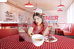 Composite image with young woman, waitress in 70s, 80s retro fashion style uniform sitting at table drinking coffee with