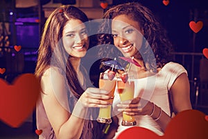 Composite image of young women toasting cocktail glasses at bar counter