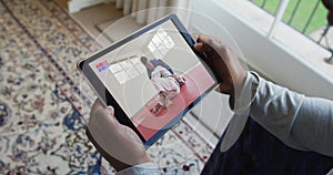 Composite of man sitting at home, watching judo match on tablet