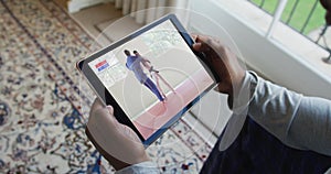 Composite of man sitting at home, watching judo match on tablet