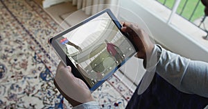 Composite of man sitting at home, watching rugby match on tablet