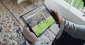 Composite of man sitting at home watching rugby match on tablet