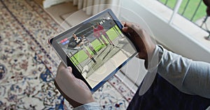 Composite of man sitting at home watching rugby match on tablet