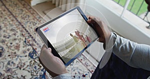 Composite of man sitting at home watching rugby match on tablet