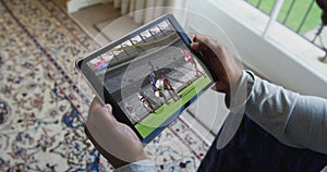 Composite of man sitting at home watching rugby match on tablet