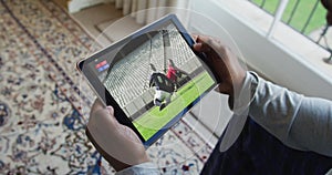 Composite of man sitting at home watching rugby match on tablet