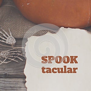 Composite of spooktacular text and halloween pumpkin and skeleton hands background