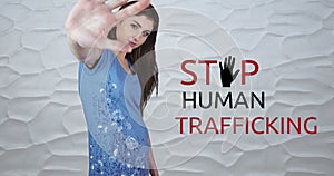 Composite of stop human trafficking text over caucasian woman showing stop sign against wall