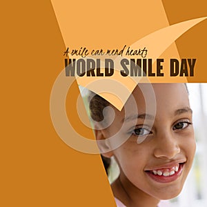 Composite of world smile day text and biracial girl smiling over pattern on brown background