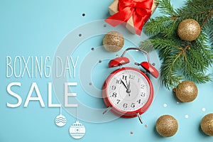 Composition with alarm clock, gift and text Boxing Day Sale on light blue background